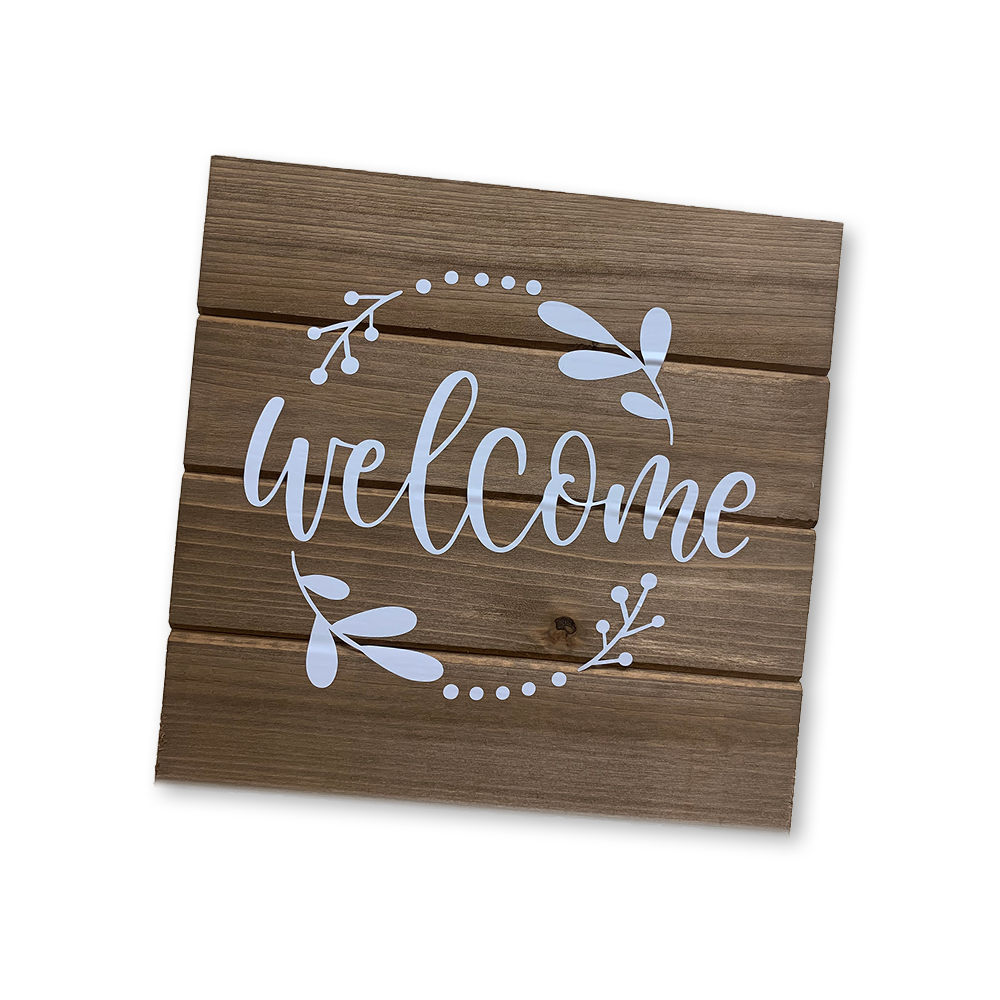Paneled wooden wall sign with white vinyl that say Welcome with a circle of leaves around it
