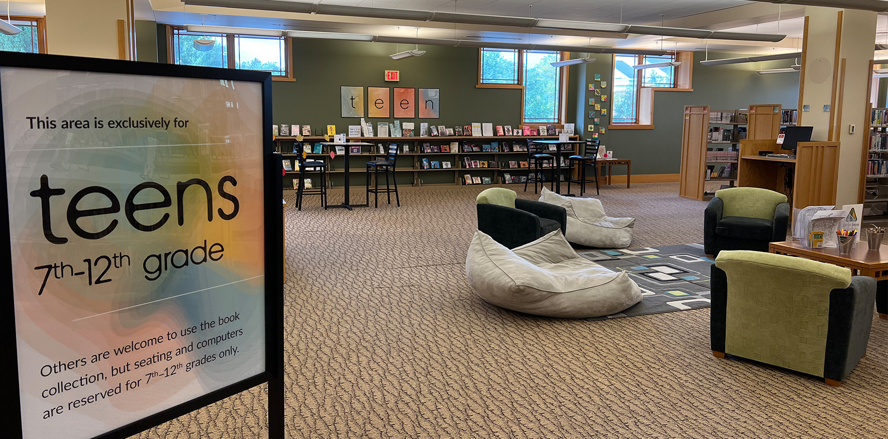 Photo of the Teen Scene, showing the hangout space with beanbag chairs and tables, and teen books and audiobooks