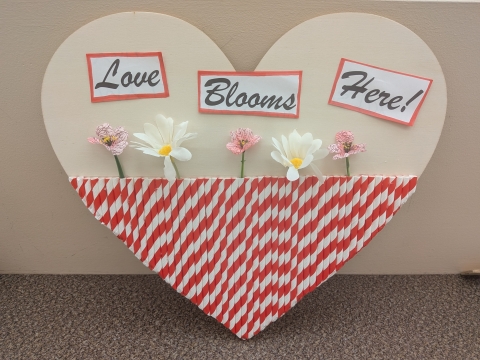 Wood heart decorated with striped straws and flowers.