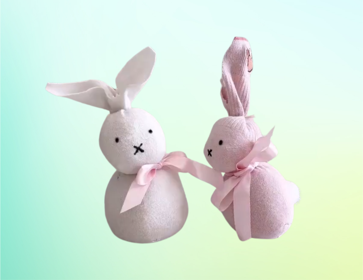 Two bunnies made out of socks in front of a blue/green/yellow background.